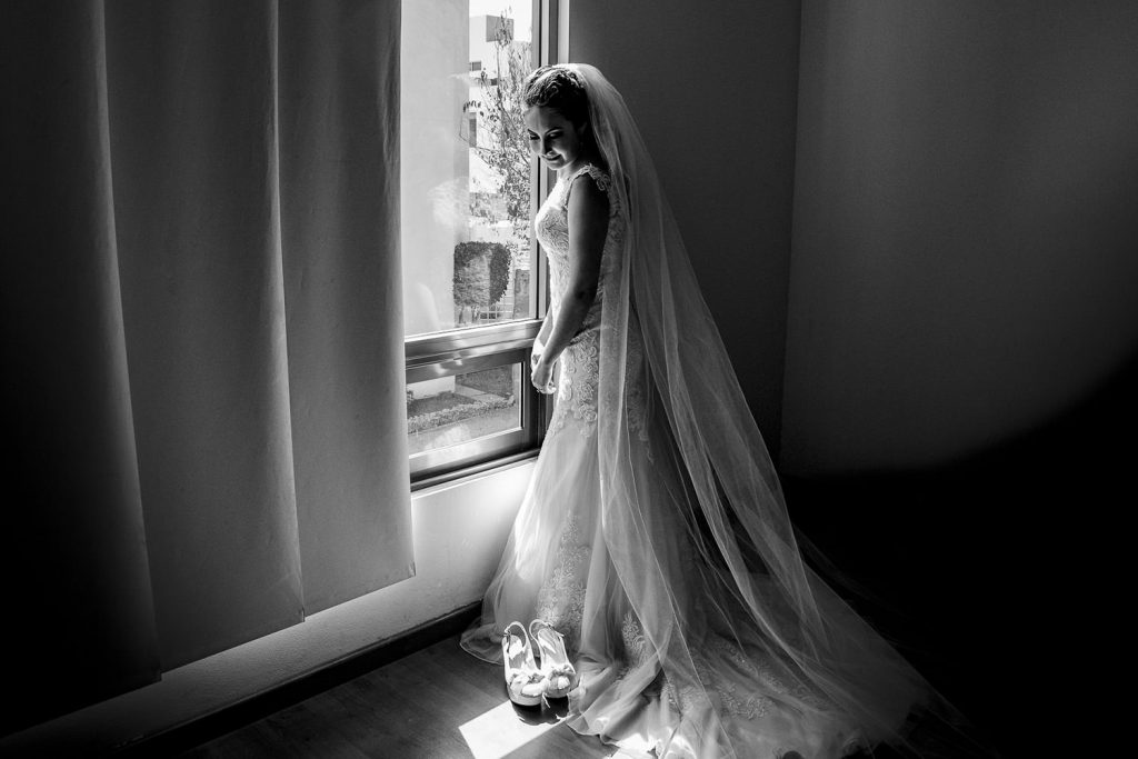 La novia junto a un ventana con luz natural blanco y negro