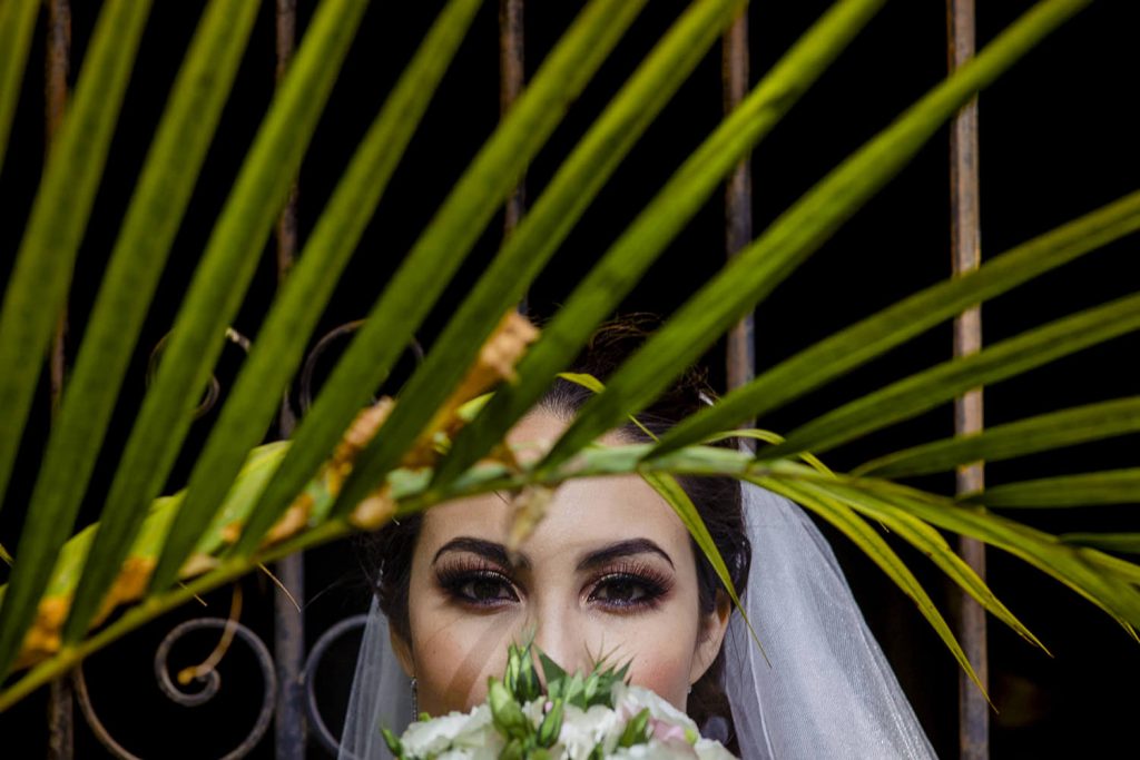 Retrato espectacular de la novia detras de una hojas